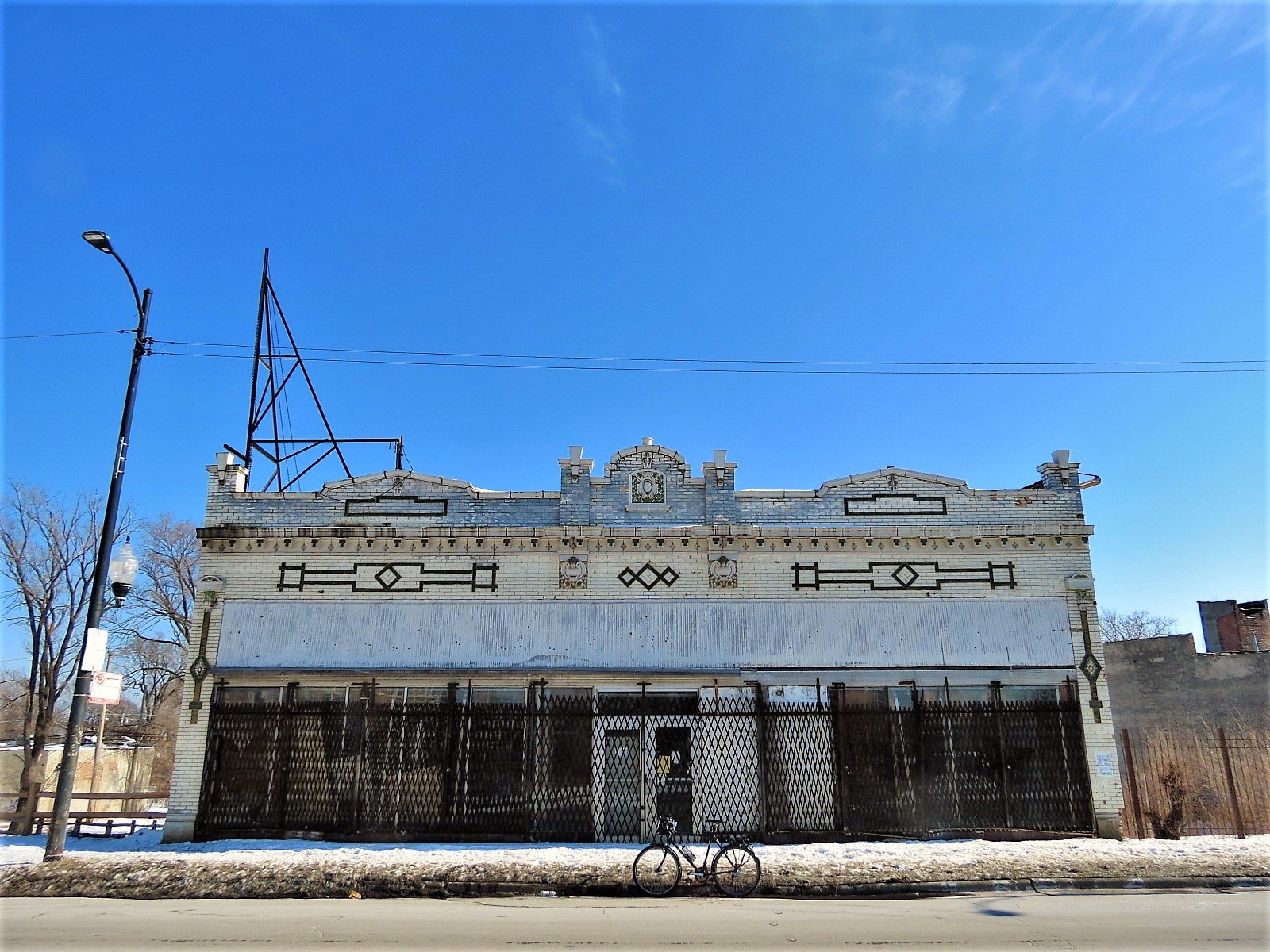 A tour bike standing at front of a green and white glazed brick double lot one story storefront.