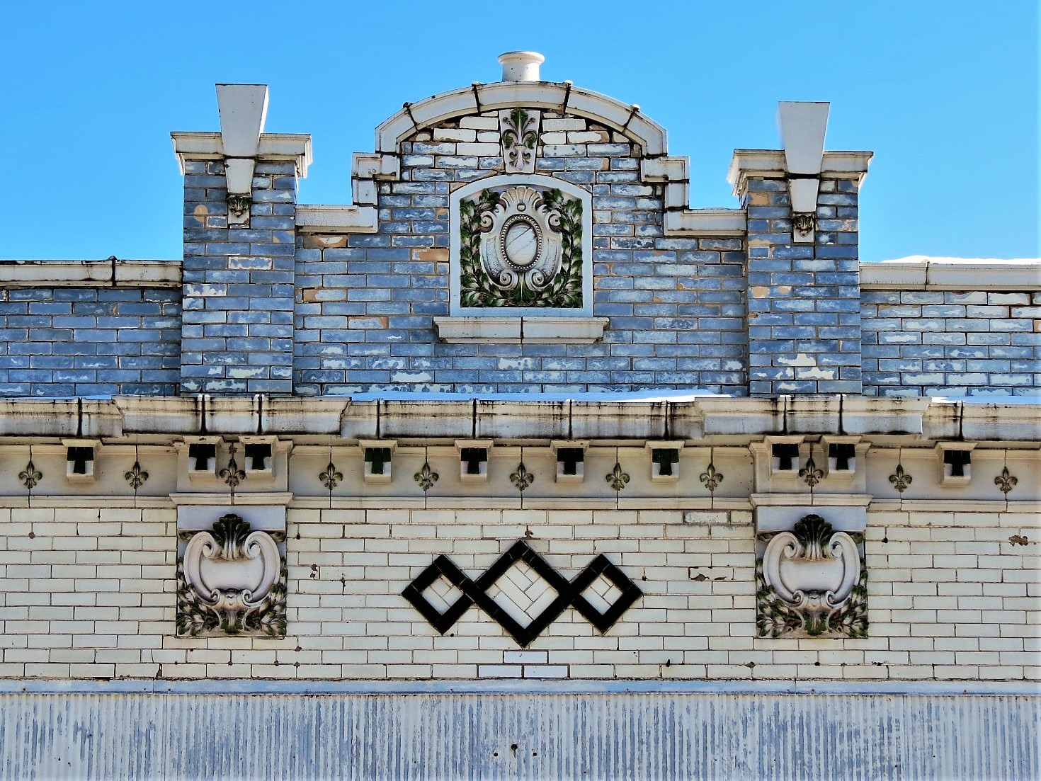 Building roofline of white glazed brick with terra cotta decoration and green glazed brick designs.