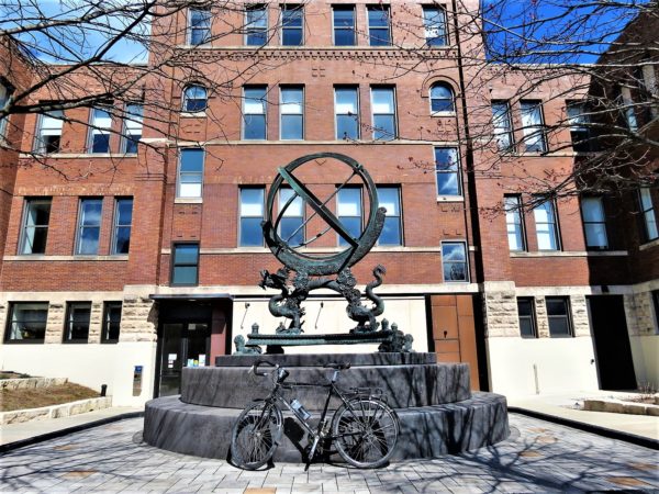 A tour bike leaning on the base of a bronze sundial device supported by a Chinese dragon.
