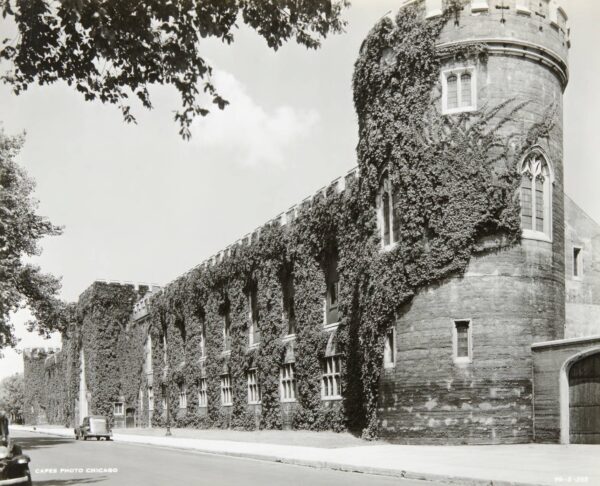 An historical black and white of an ivy covered castle like Stagg Field with a round corner tower and crenellation across the top.