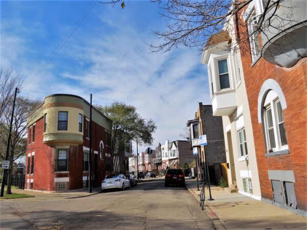 A tour bike at the side of a street with 19th century bay windows and turrets and rowhouses in the distance.