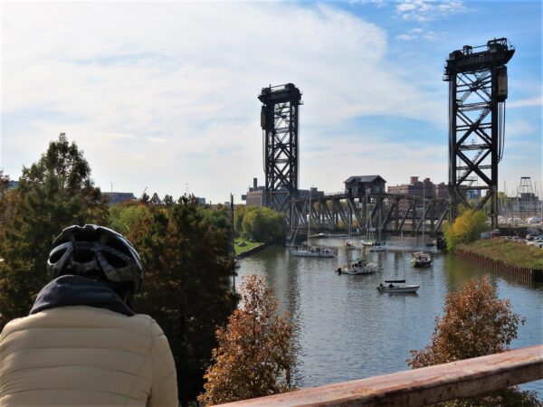 A CBA tour rider looking at the Chicago River with sailboats waiting for a steel vertical lift bridge to raise.