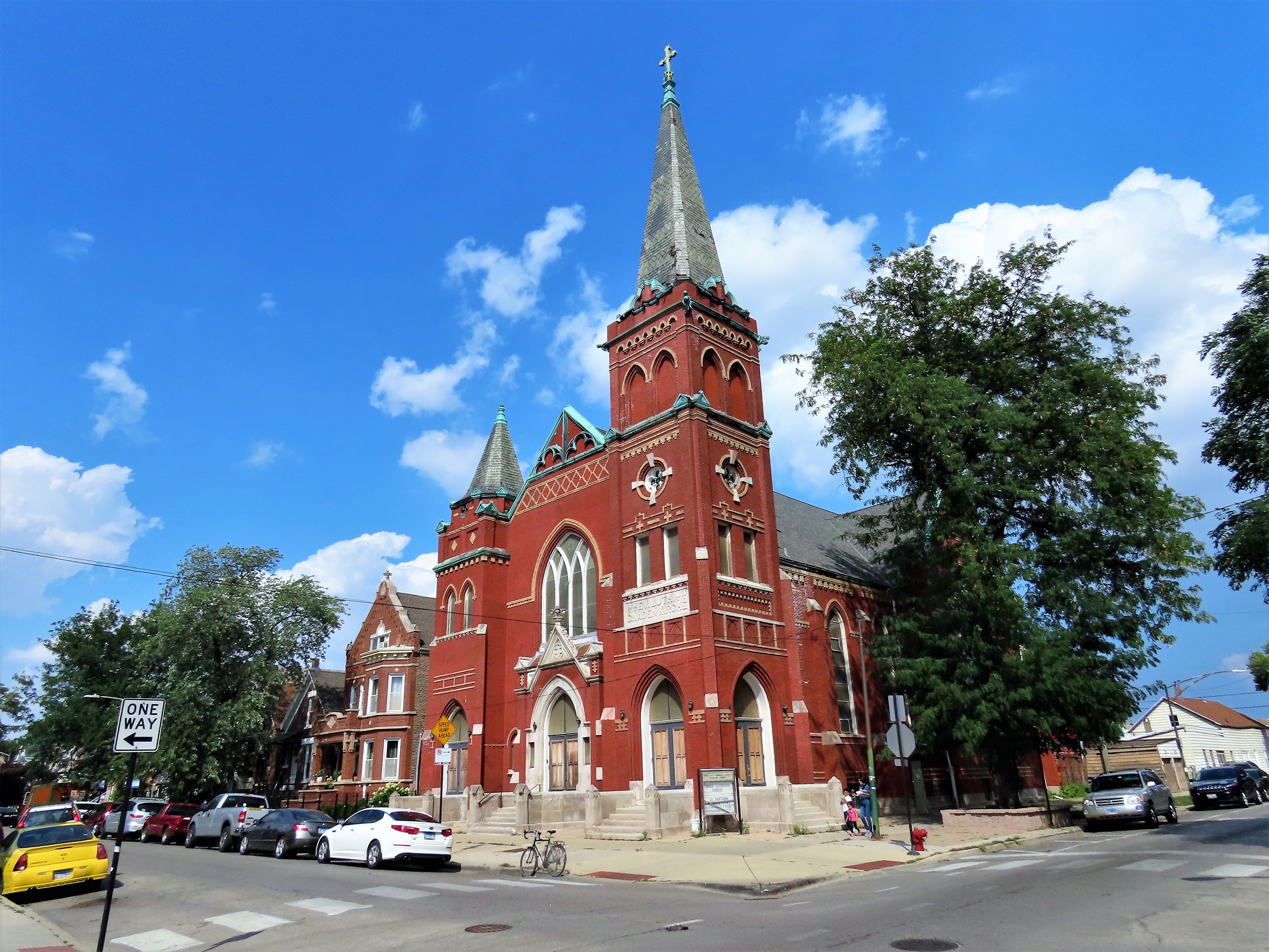 A tour bike standing in front of a corner lot red brick and tan bricked detailed Lutheran Gothic Revival church