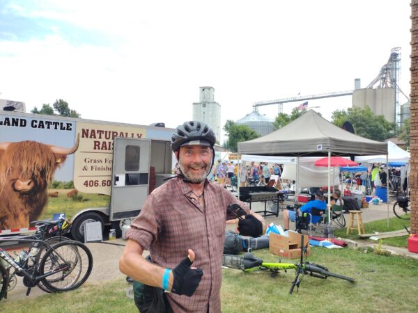 Me giving a double thumbs up with vehicles and a grain elevator behind.