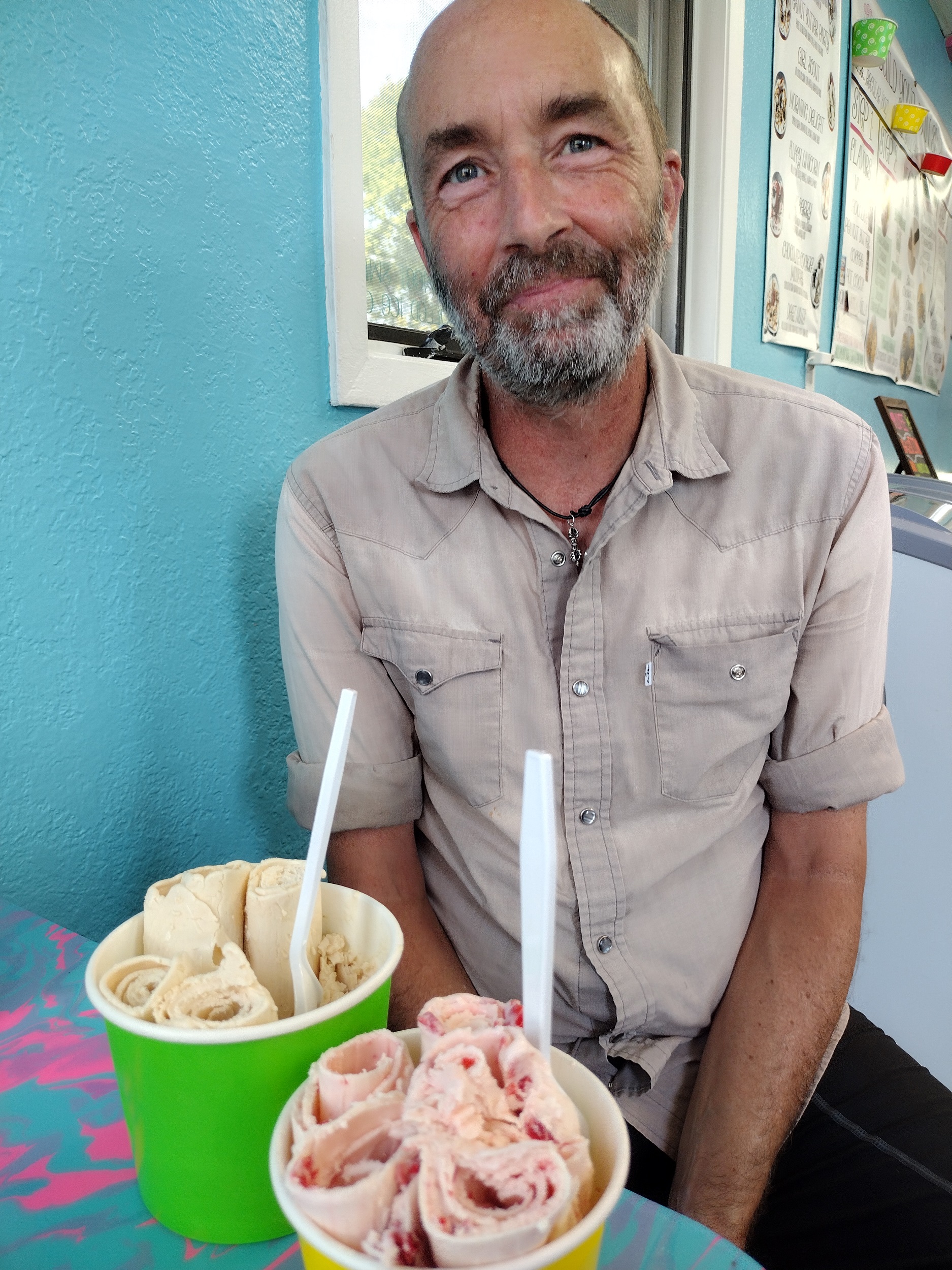 Me smiling with two containers of rolled ice cream in front of me