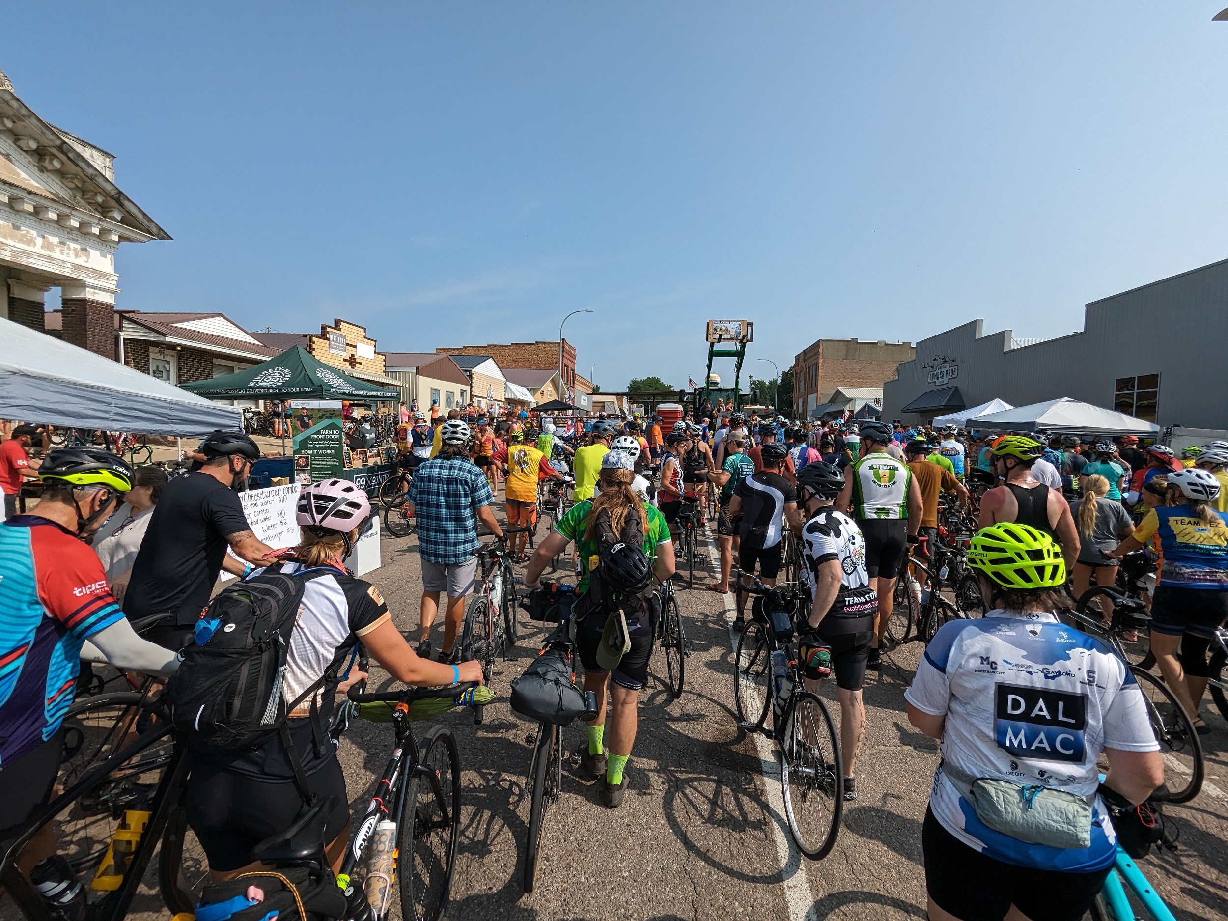 A large crowd of cyclists walking their bikes on a small town street