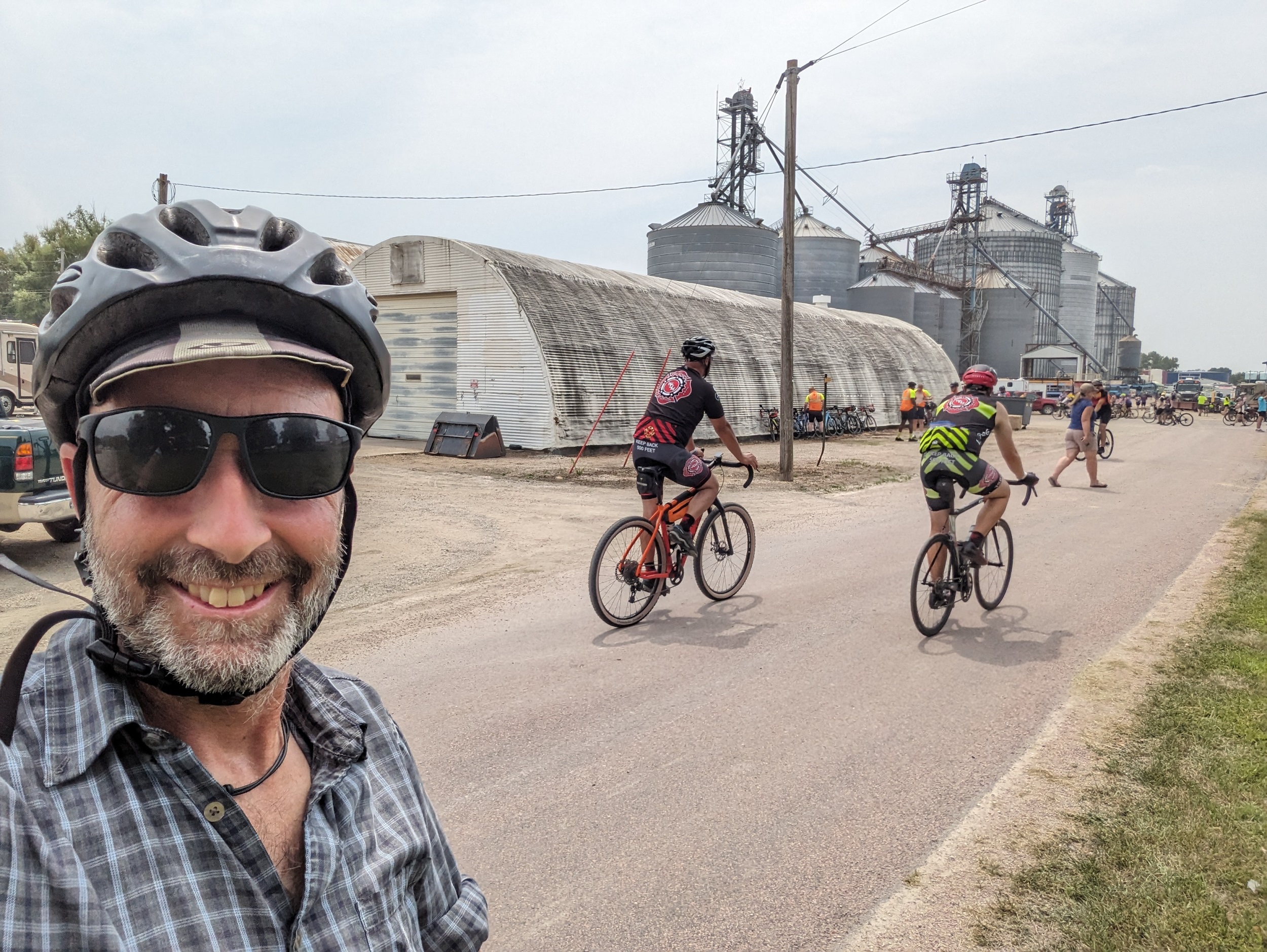 Me looking at the camera with grain facilities and cyclists behind.