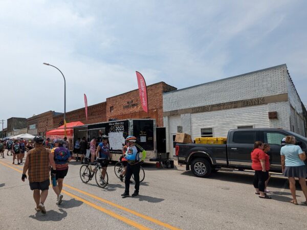 A brick small town main street crowded with cyclists.