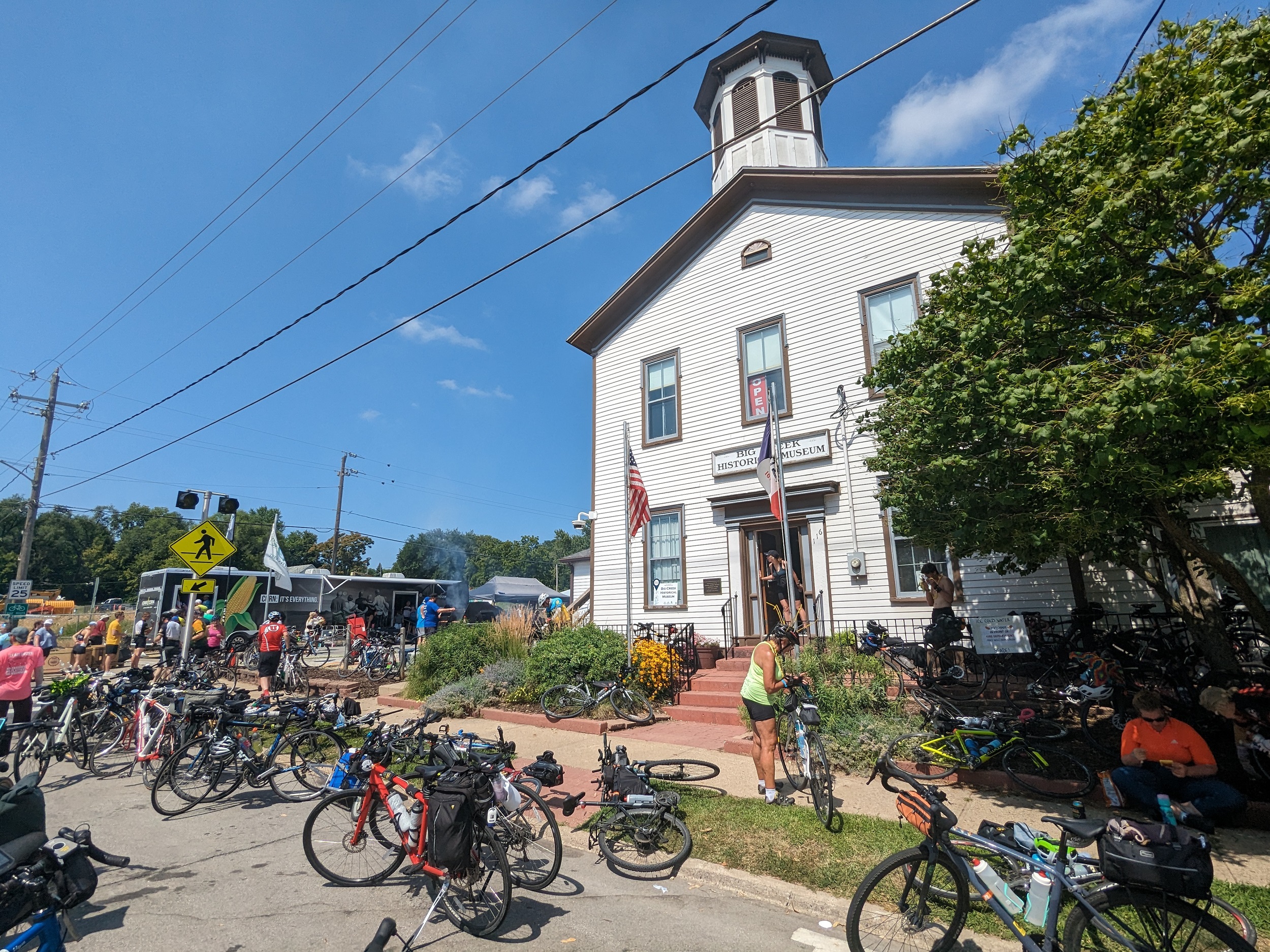 A white two story wood building with small roof tower, bicycle lay everywhere