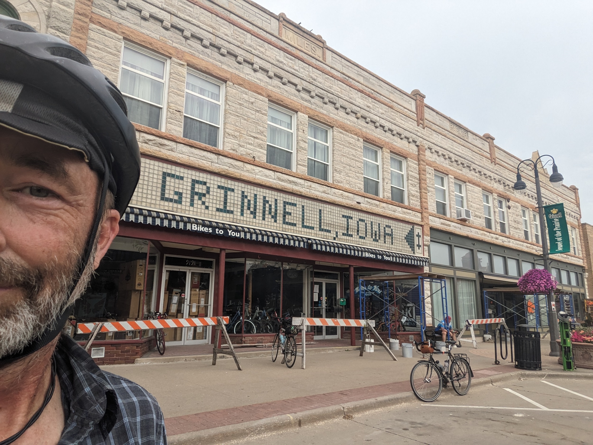 Half of my face with a creme limestone two story storefont a flat block with a green and white tile entry sign Grinnell, Iowa.