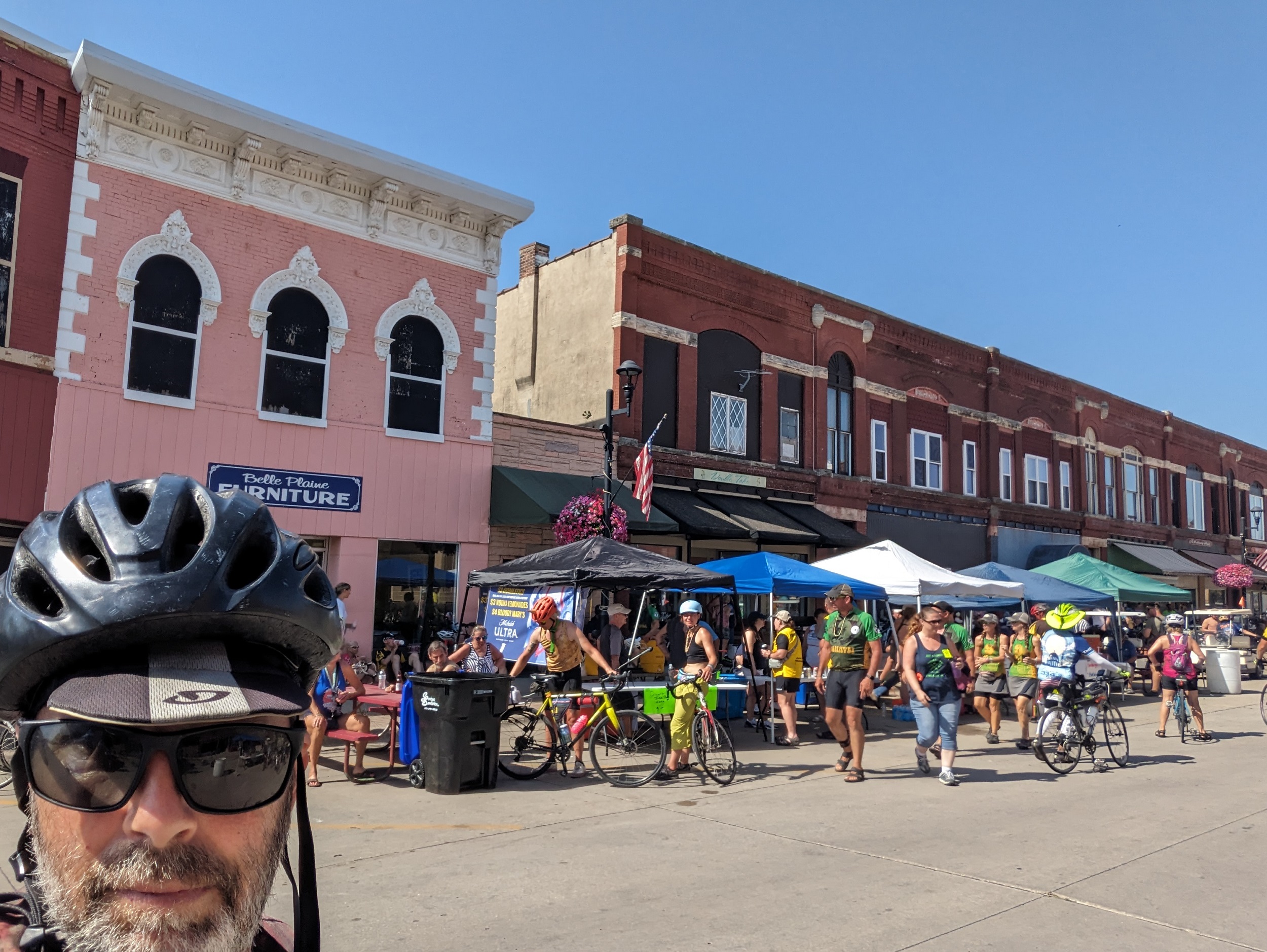 Me with cyclists and service tents along an uninterrupted block of late 19th Century downtown buildings.