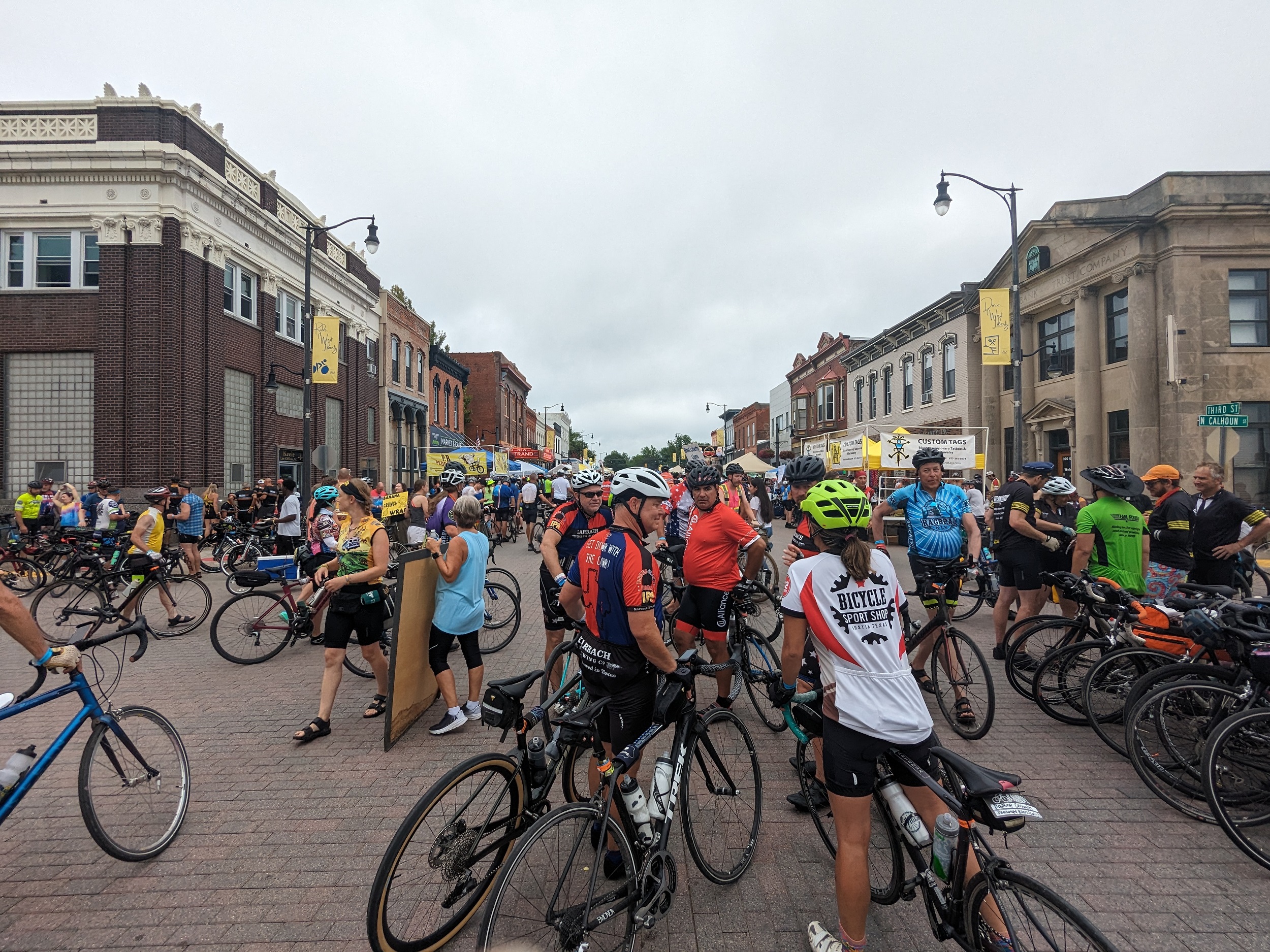 Numerous cyclist filling the main street of a turn of the century small town main street.