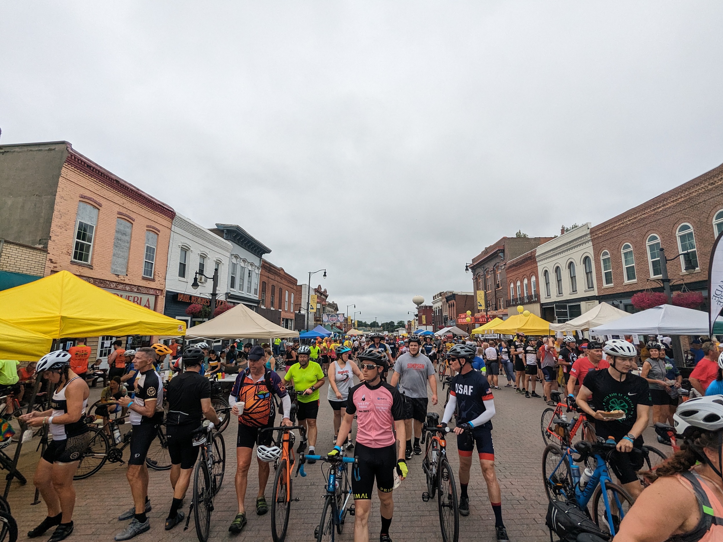 Numerous cyclist filling the main street of a turn of the century small town main street.