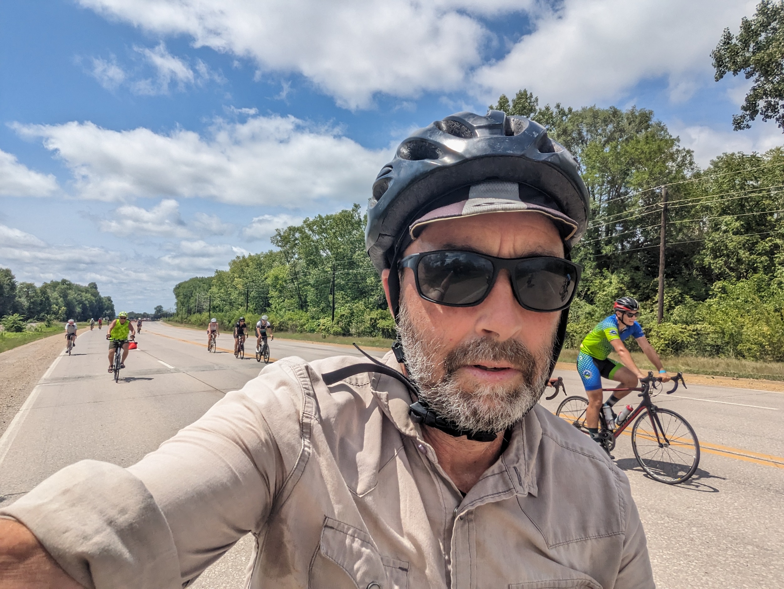 Me looking at the camera while riding the bike, other cyclists are behind and to my left.