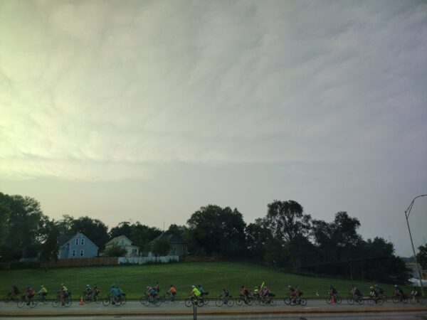 A stream of bike riders on the street in the morning light.