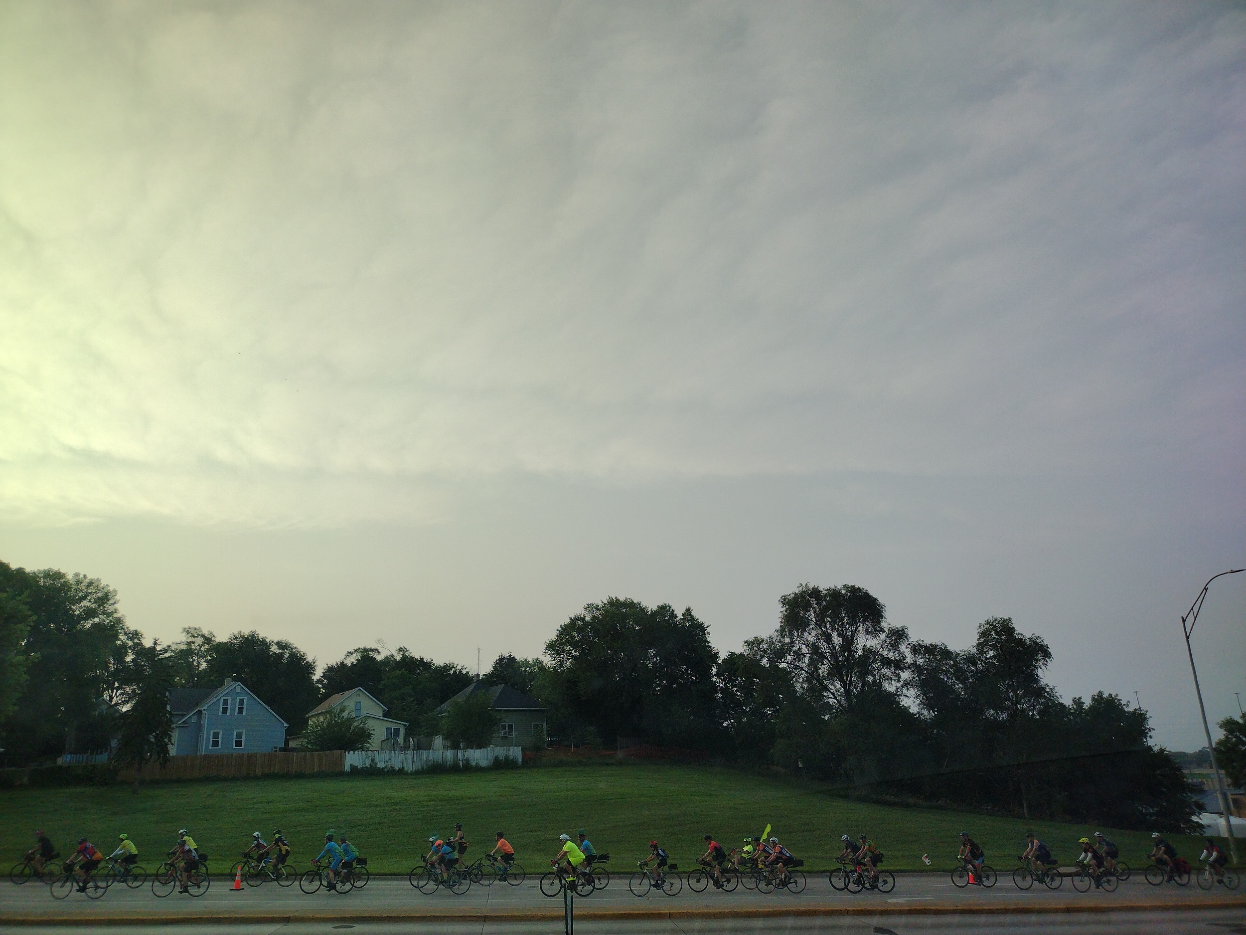 A stream of bike riders on the street in the morning light.