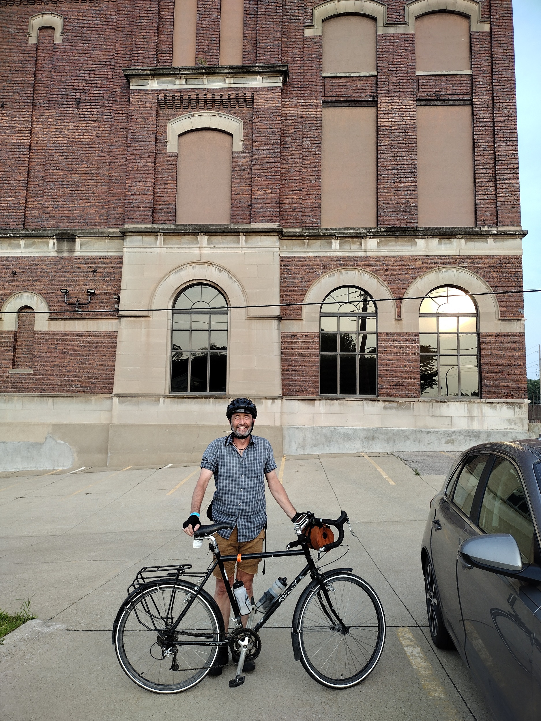 Me and my bike with a brown brick former brewery in the back.