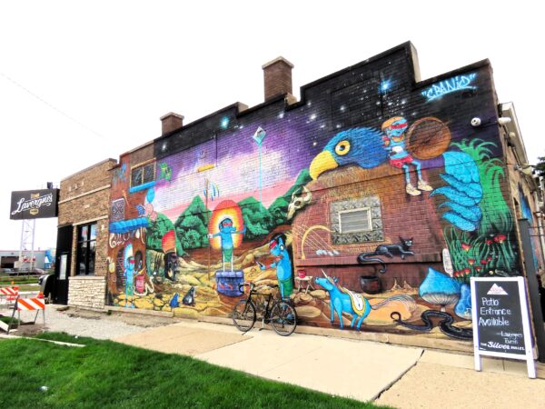 A tour bike leaning on fantastical mural with blue indigenous people interacting with technology.