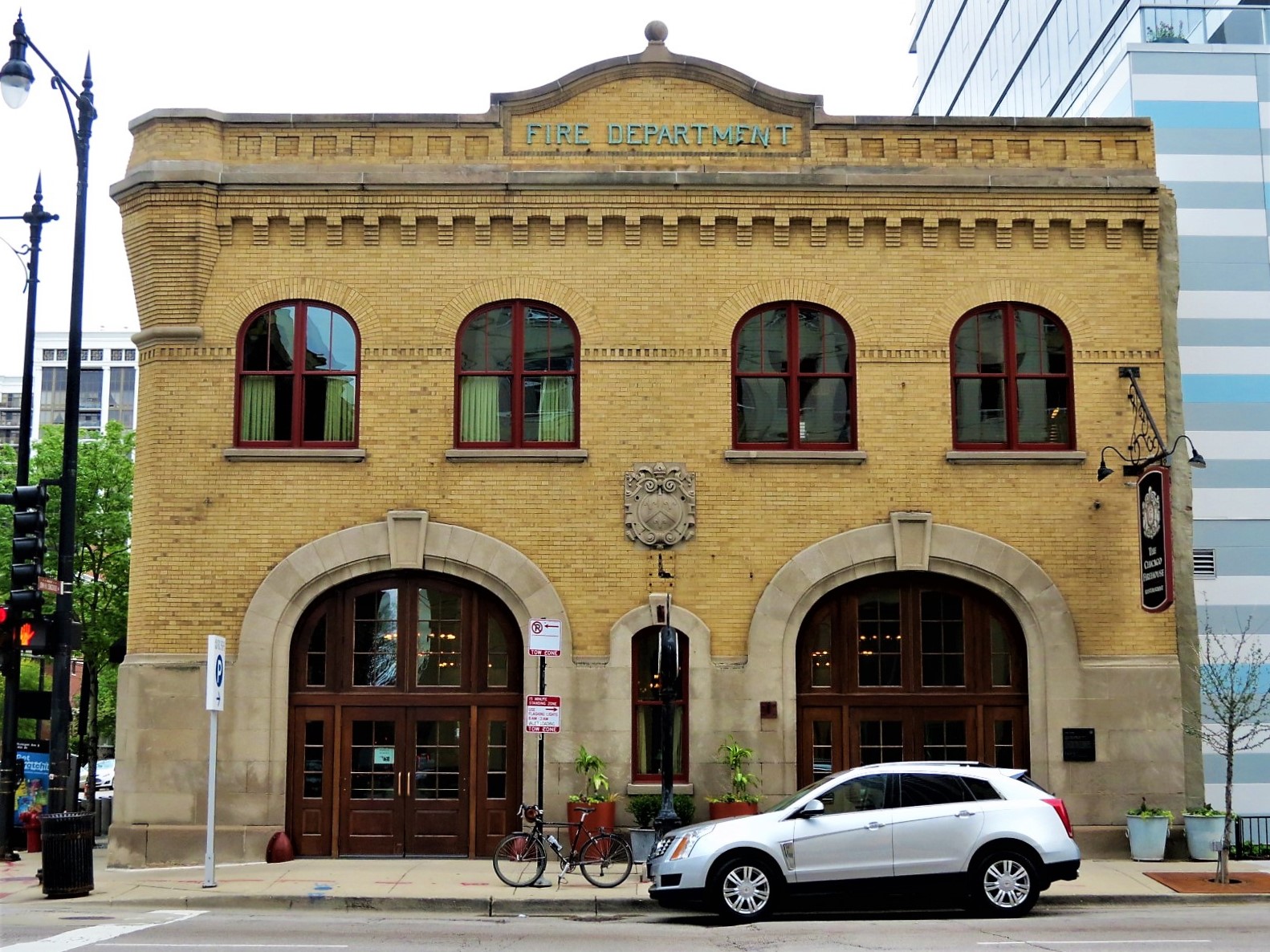 A tour bike standing at front of a two story double limestone outlined bay door former fire house.