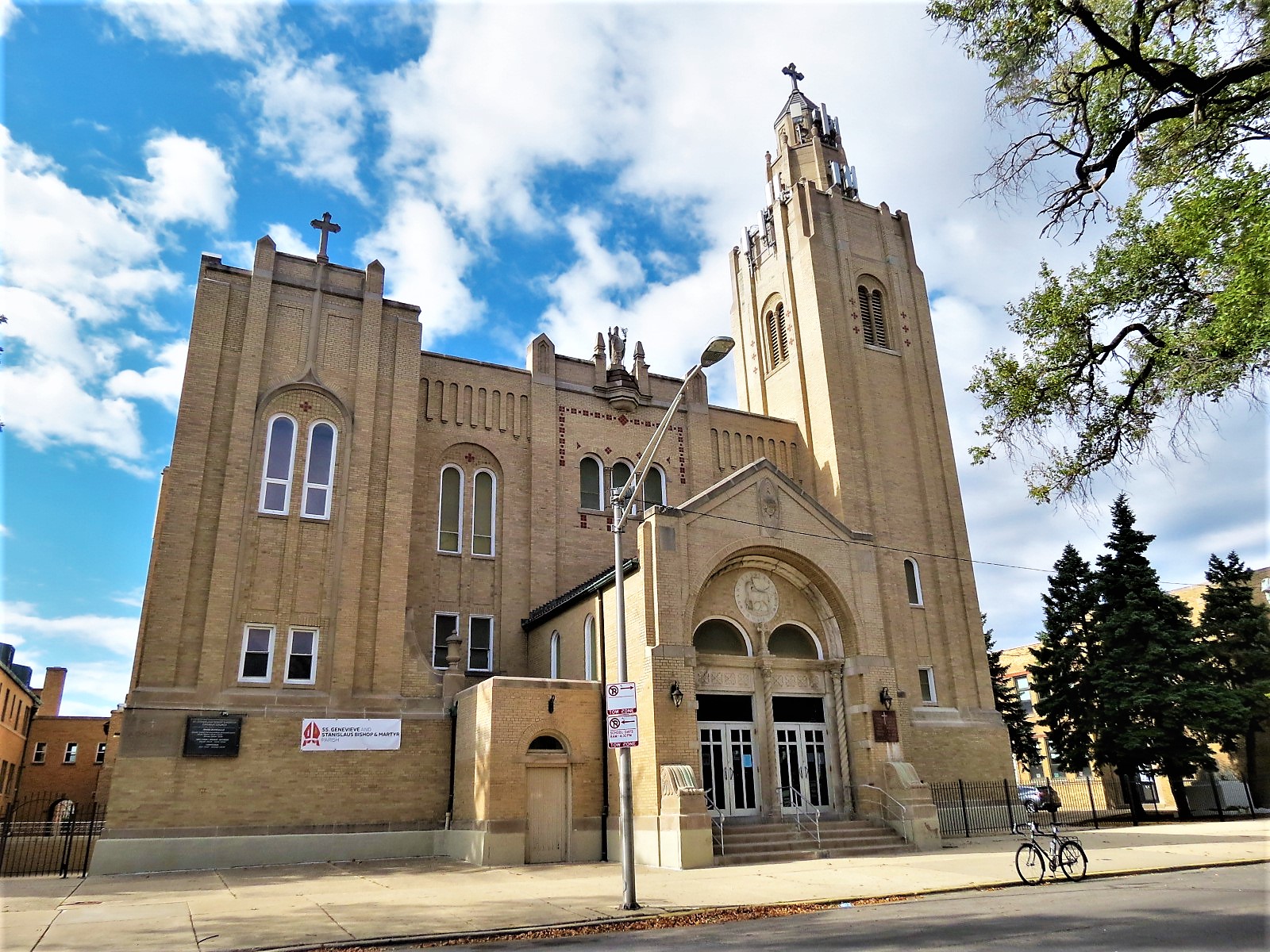 A tour bicycle standing at front of a yellow brick Gothic Revival church with a single corner bell tower and metal steeple.