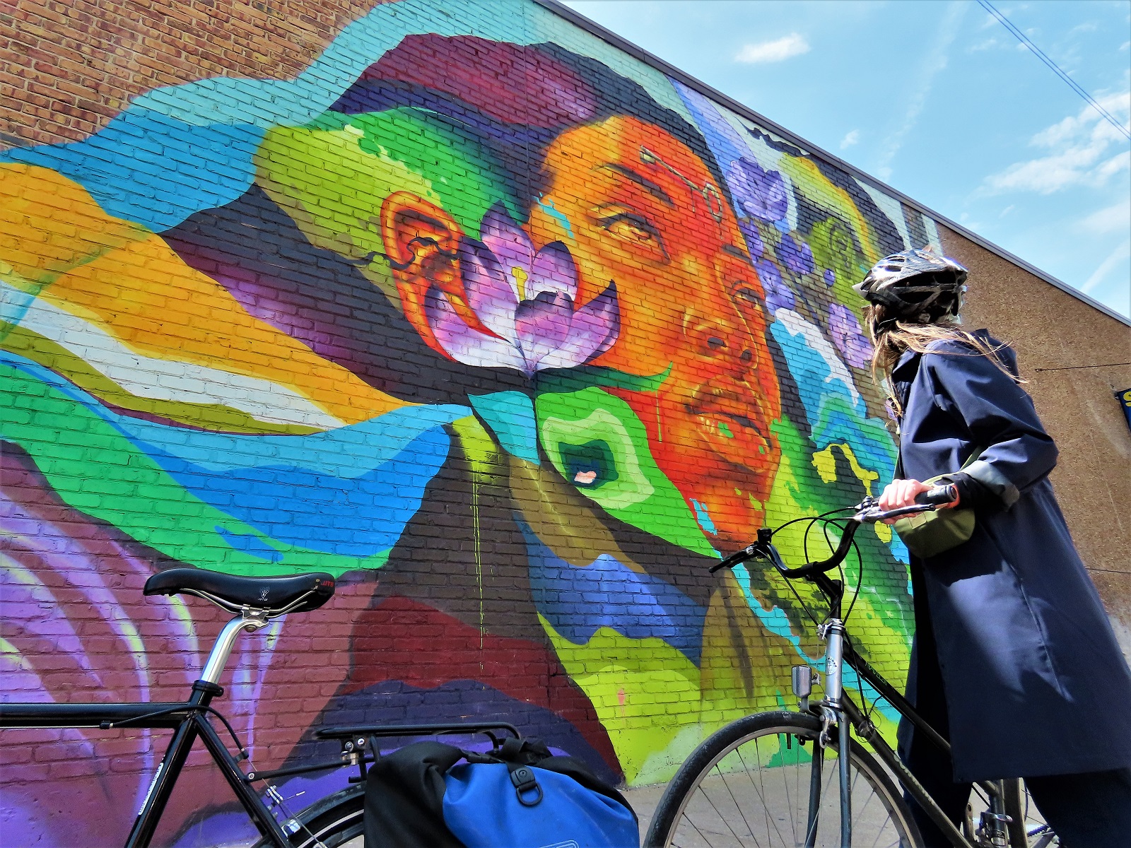 A CBA rider getting a close look at a bright colored mural of a Black woman looking into the distance.