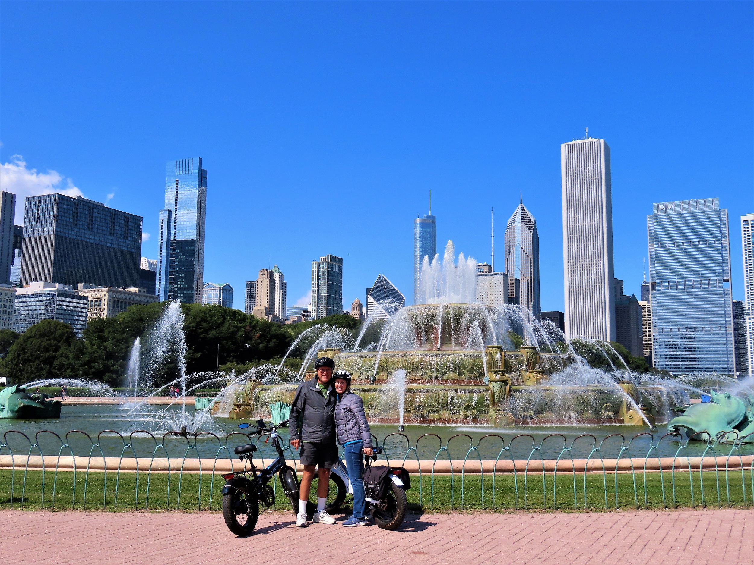 Two smiling CBA riders with Chicago's skyline and Buckingham Fountain in the background. 
