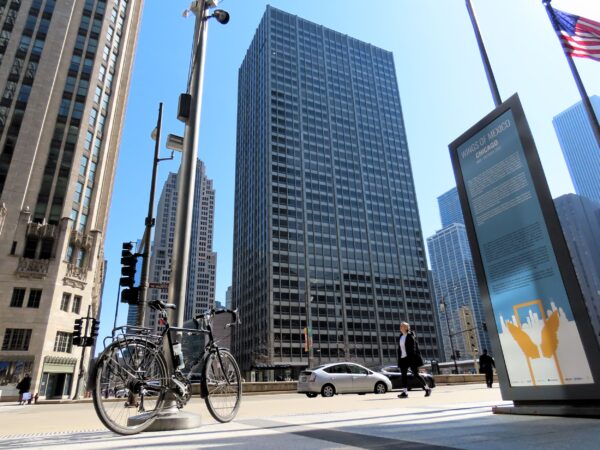 A tour bicycle in the fore with a thirty story black steel and glass International Style building behind.