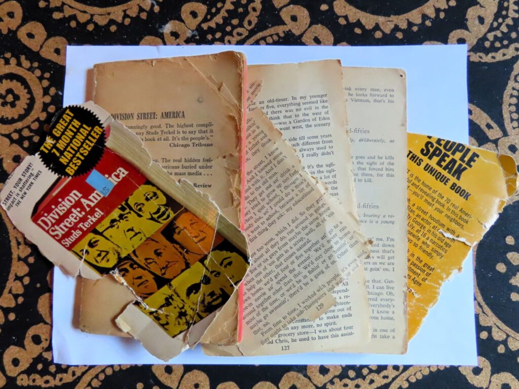 A well used paperback book in at least six pieces laying on a white sheet of paper.