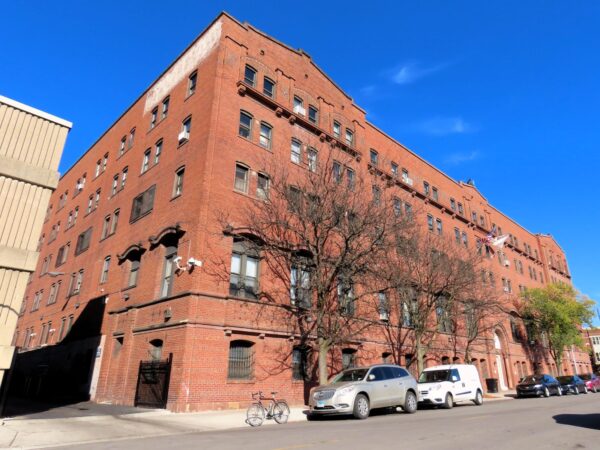 A tour bike standing at the bottom of an early 1900s large block five story red brick YMCA building.