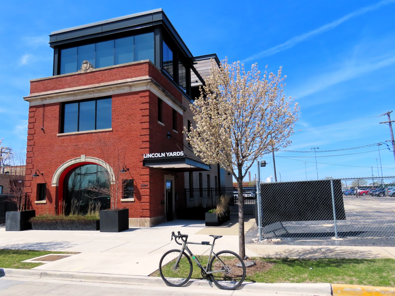 A tour bicycle standing at front of a modernized two story red brick former firehouse with an arched front bay door and a modern glass third story.