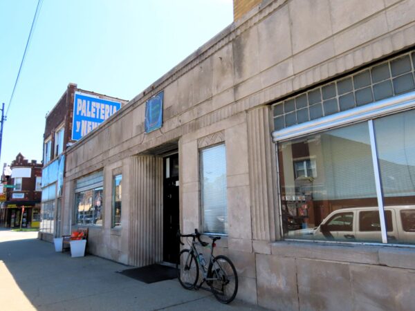A tour bicycle leaning next to the central door of a 1930s Art Deco one story limestone faced former bank.