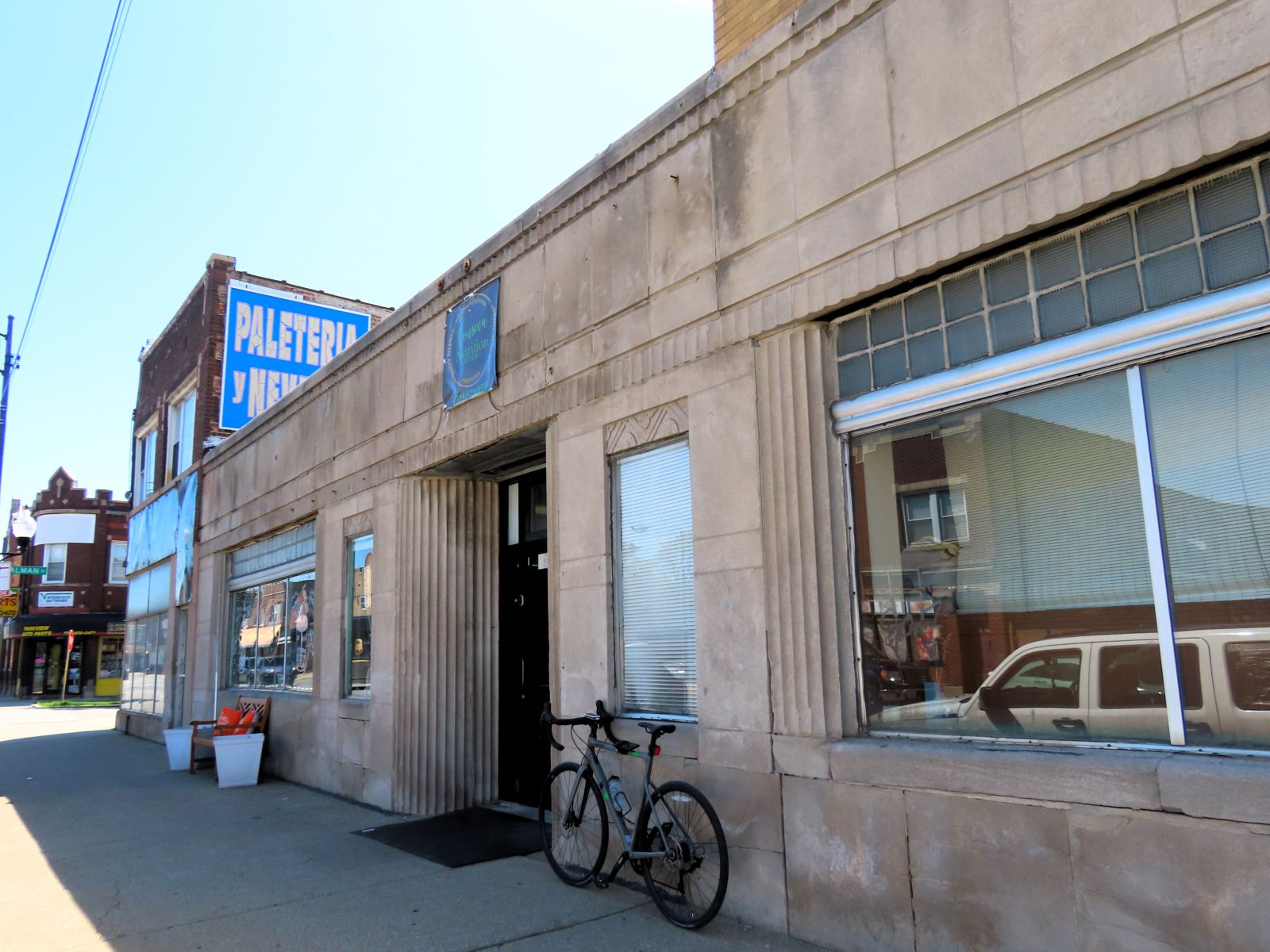 A tour bicycle leaning next to the central door of a 1930s Art Deco one story limestone faced former bank.