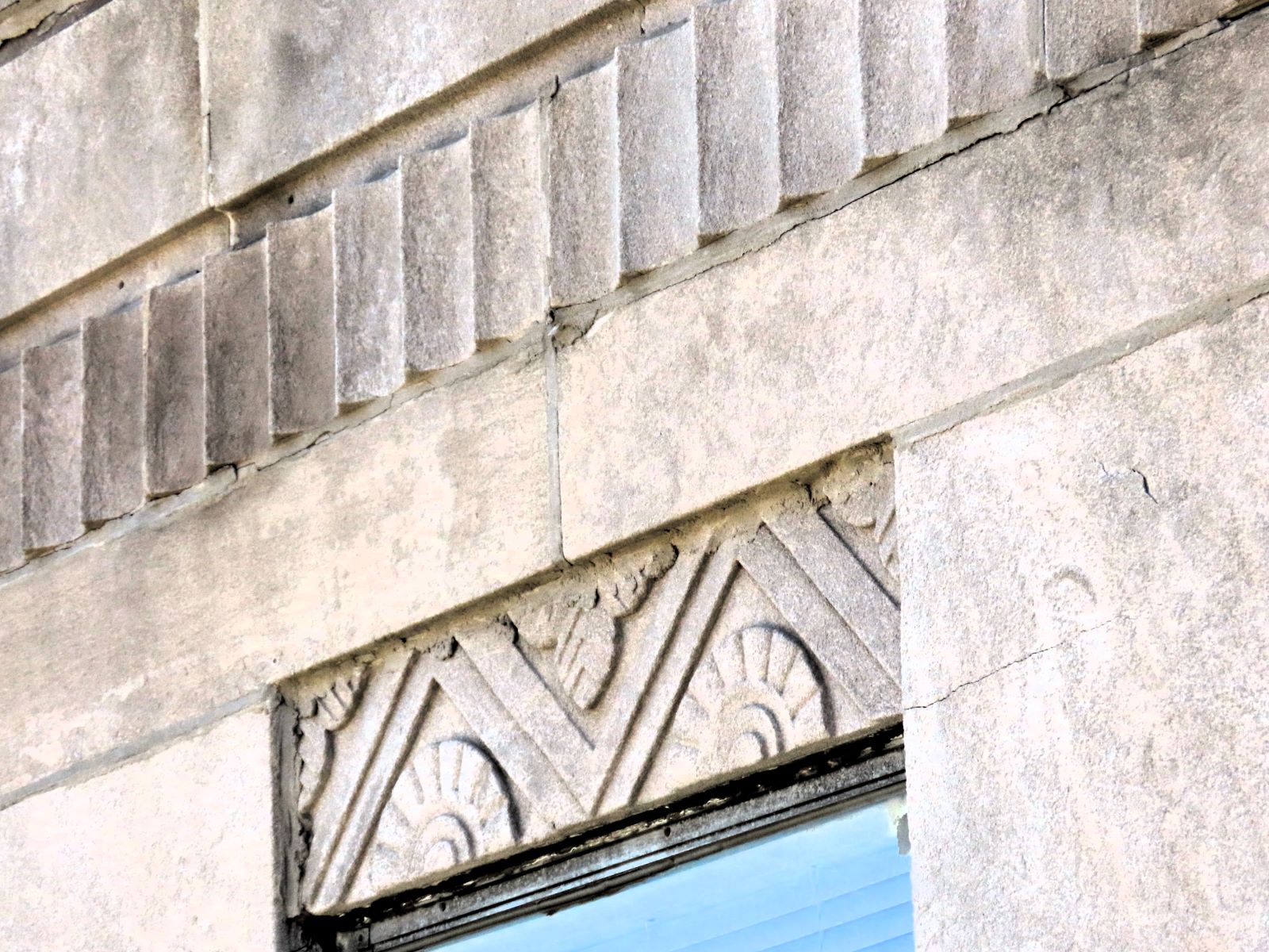 A buildng closeup of Art Deco designs limestone above a window.
