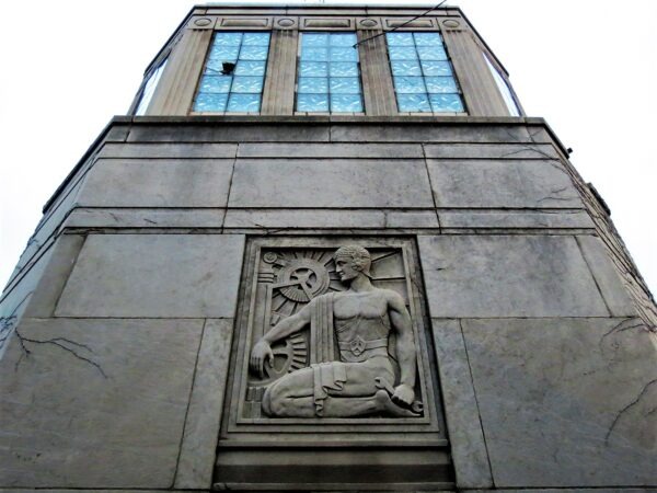 An Art Deco bridge minder house with a relief of a figure working with cogs.