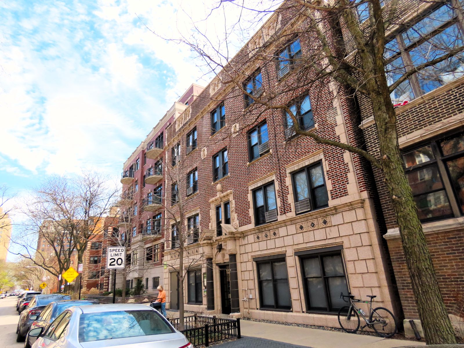 A tour bike leaning on the bottom of a 1920 four story brown brick and tan terra cotta former hotel now apartments.